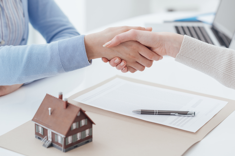 mortgage broker and customer shaking hands after signing a contract