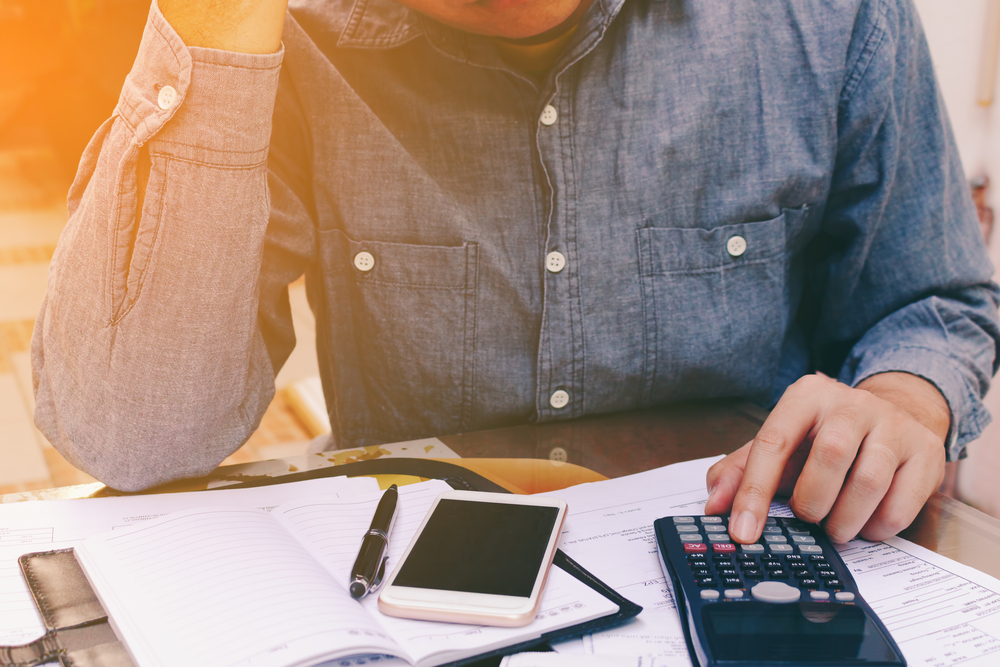 stressed man using calculator to figure out bills