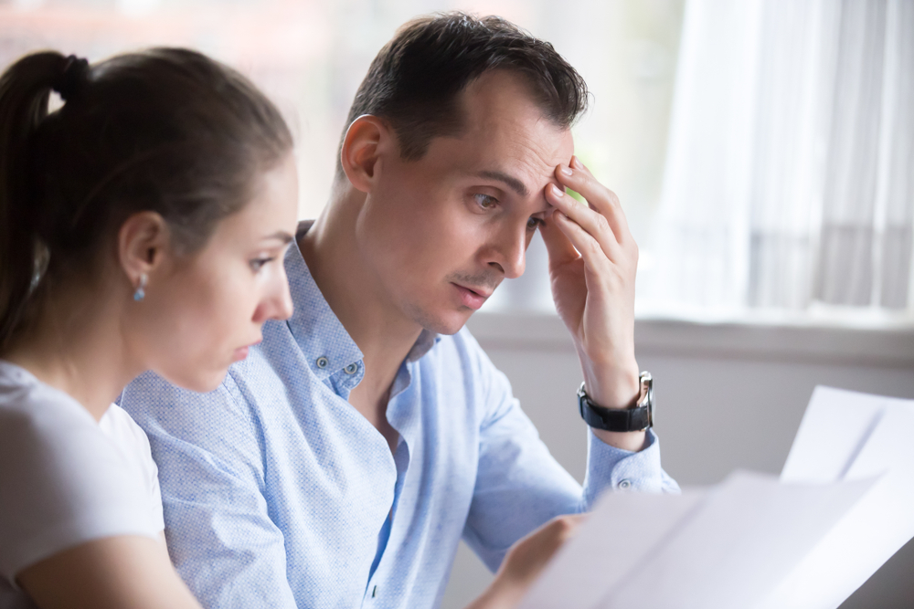 couple looking worredly at paperwork