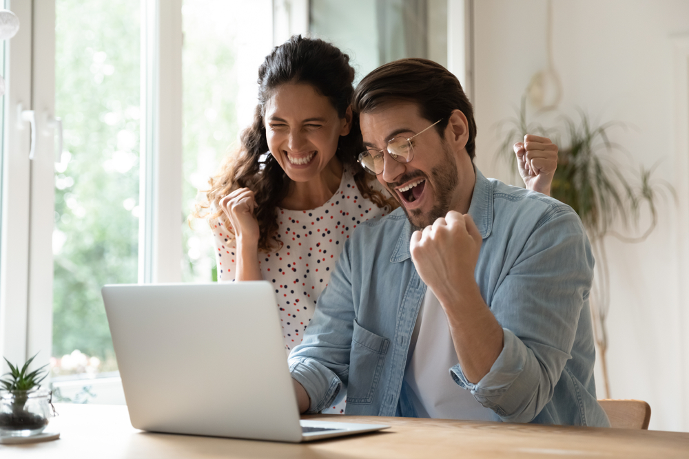 happy couple looking excitedly at laptop